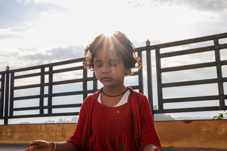 a young child in front of a fence doing meditation