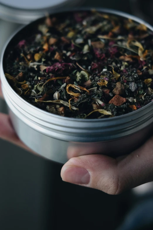 someone is holding their hand around a canister filled with flowers