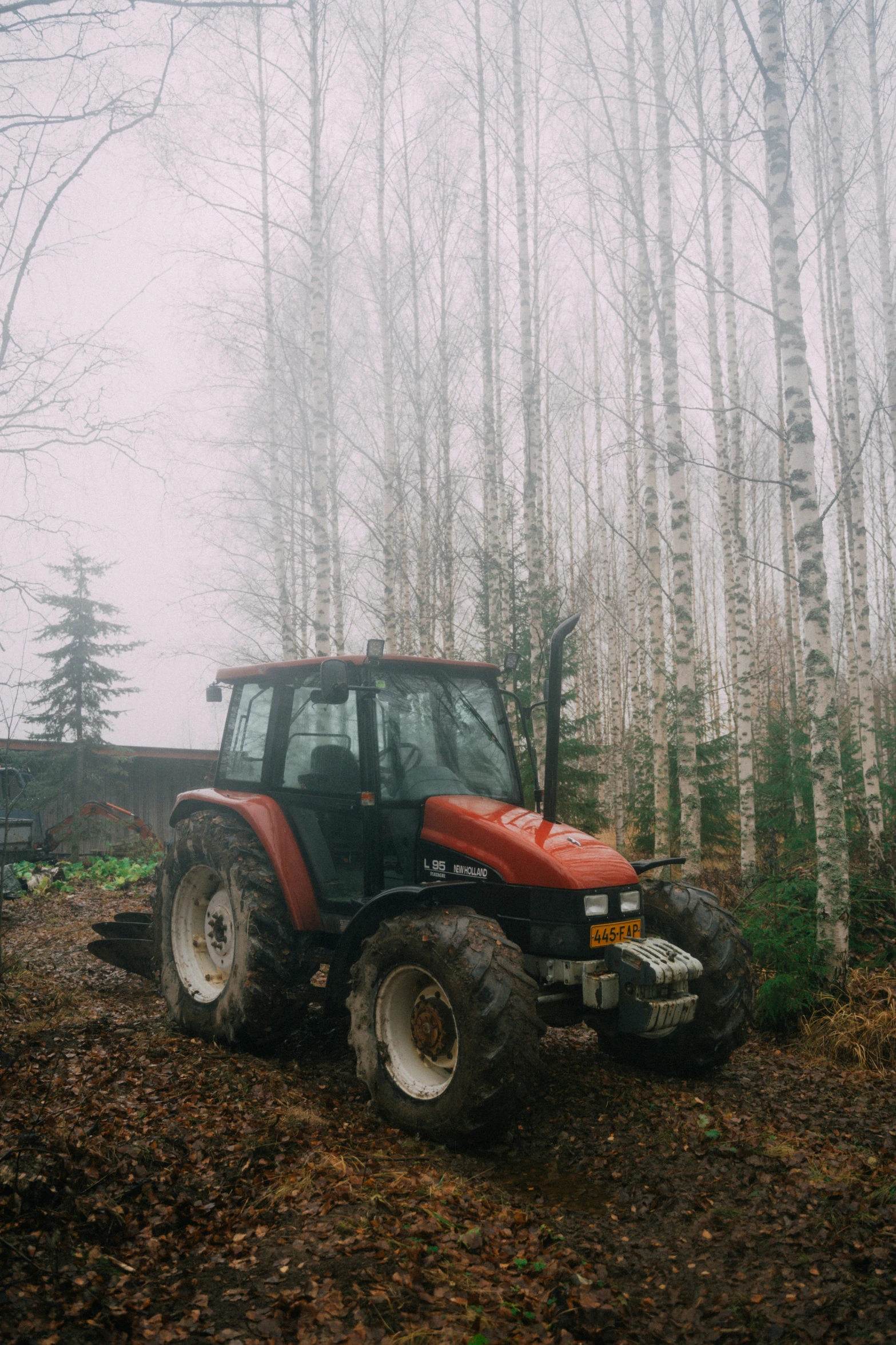 a tractor is moving across a forest covered in fog