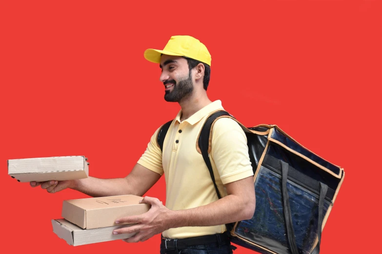 a man in yellow is carrying two boxes