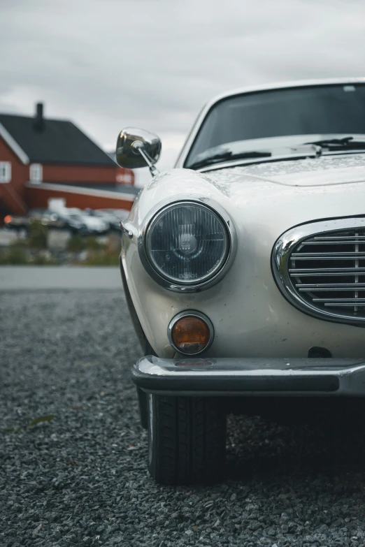 an old classic looking white mercedes sits on gravel