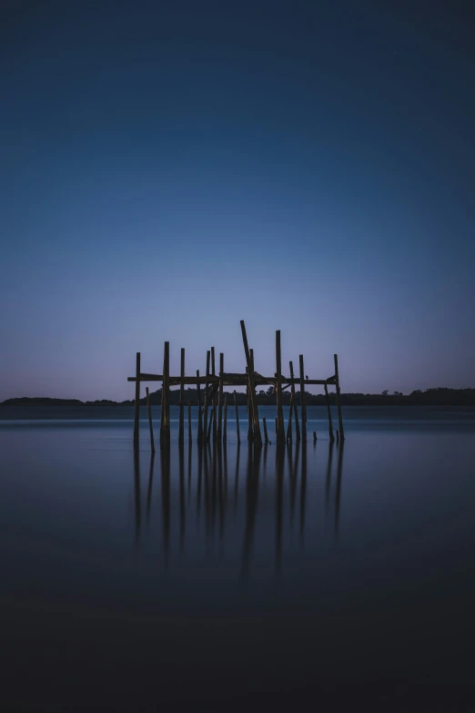 a row of wooden posts on the edge of water