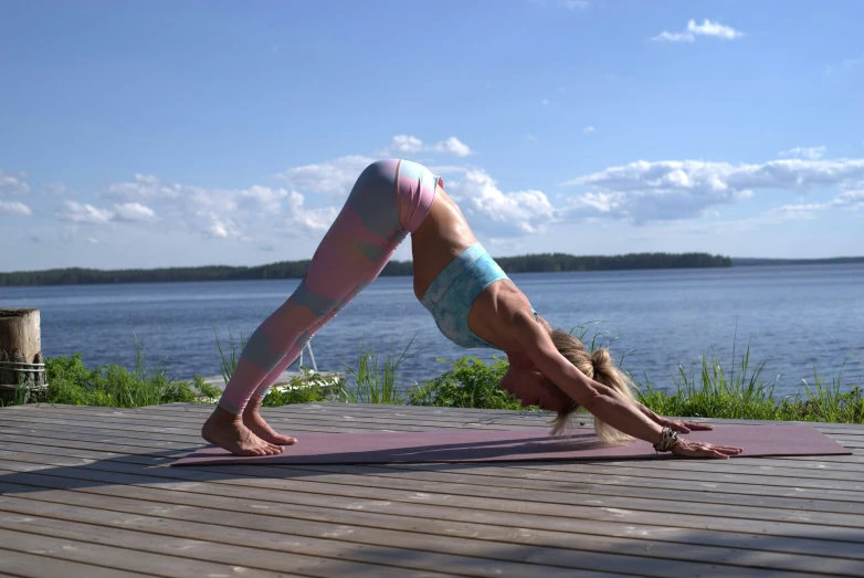 woman doing a yoga downward position by the lake