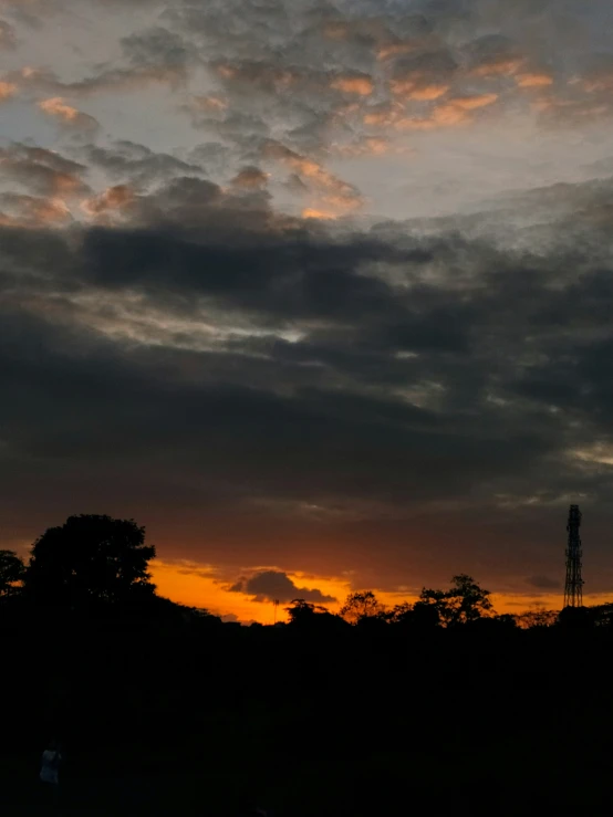 a cloudy sunset as people stand around in a field