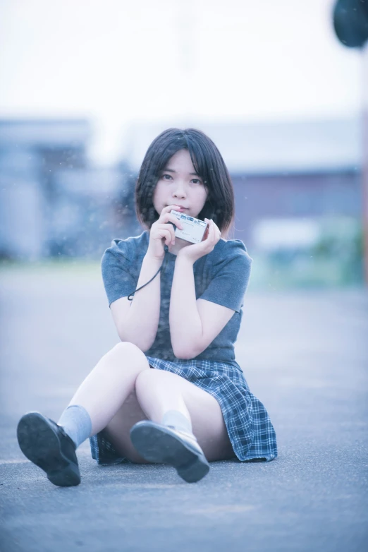 a little girl wearing a blue dress sitting down and holding a cell phone