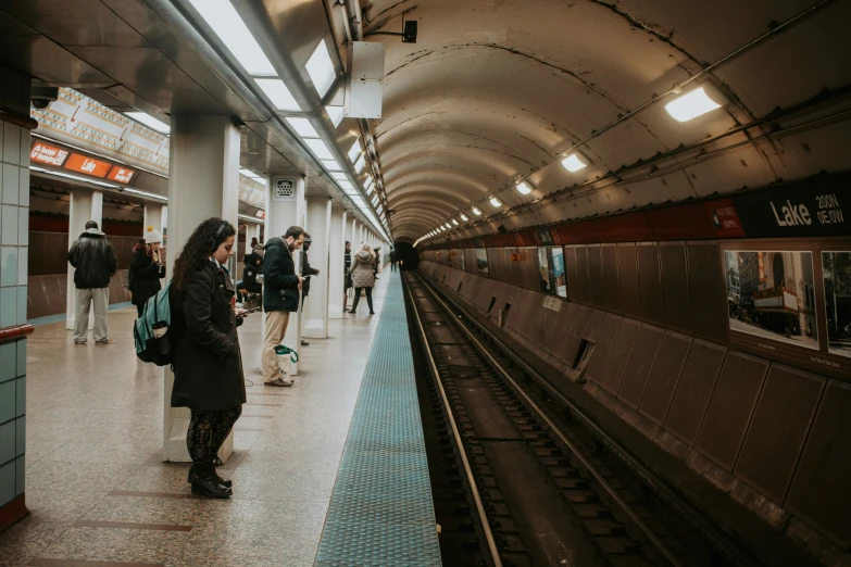 people wait to board a train on the subway