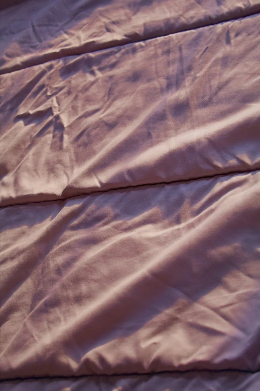 a white bed sheet with the sheets covered in light purple colored material