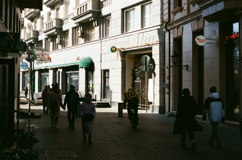 pedestrians walk along the sidewalk next to a building