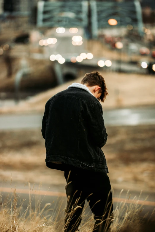 a person standing on a road surrounded by a field