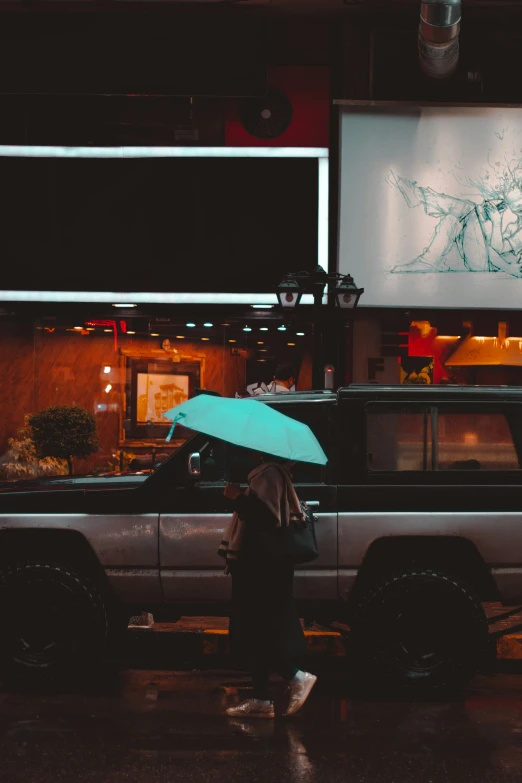 a person with a blue umbrella walks down the sidewalk