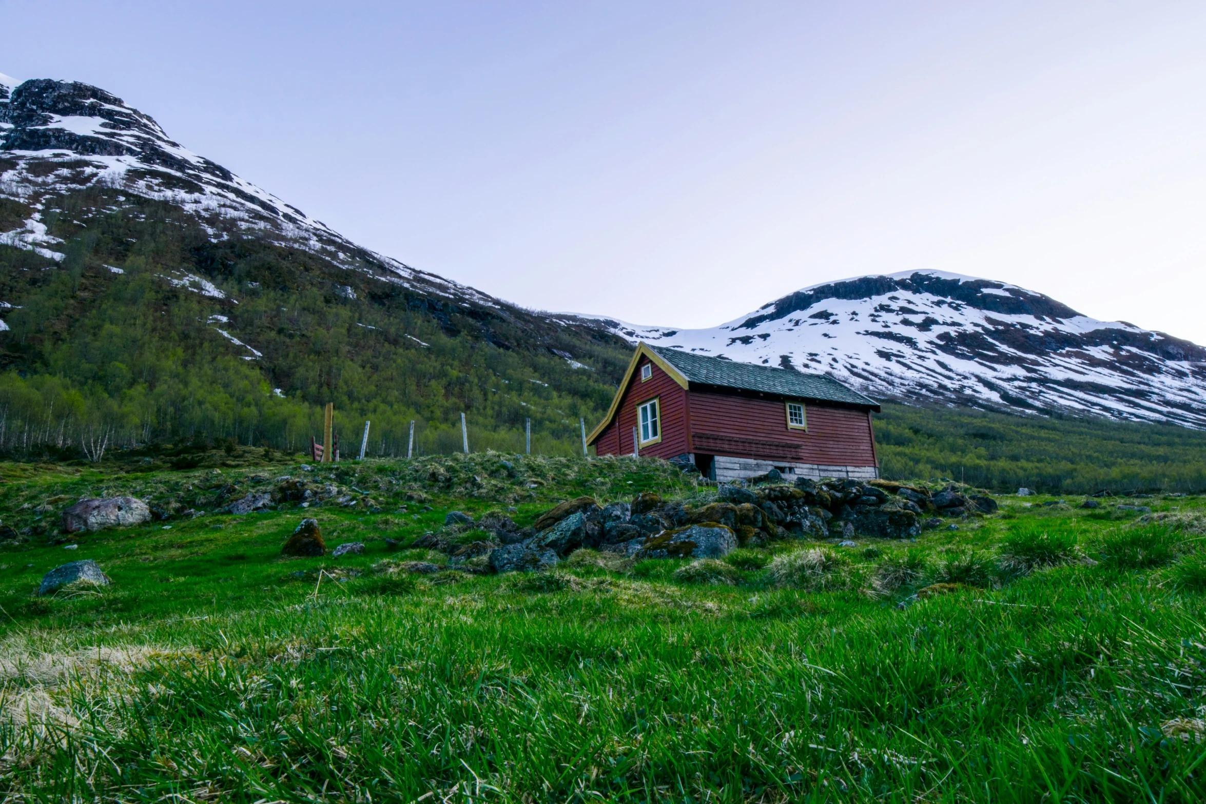 a small cabin is on a hill near the mountain