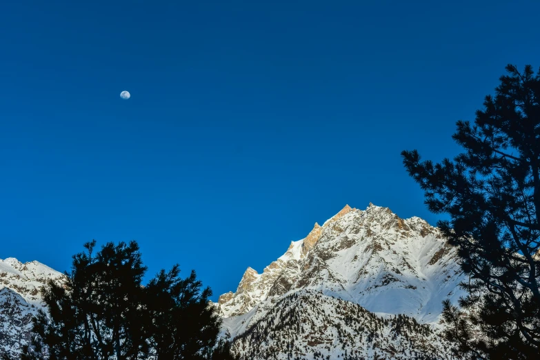 the moon is in the distance above some mountains