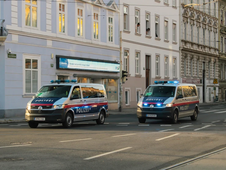 police cars driving down the street next to tall buildings