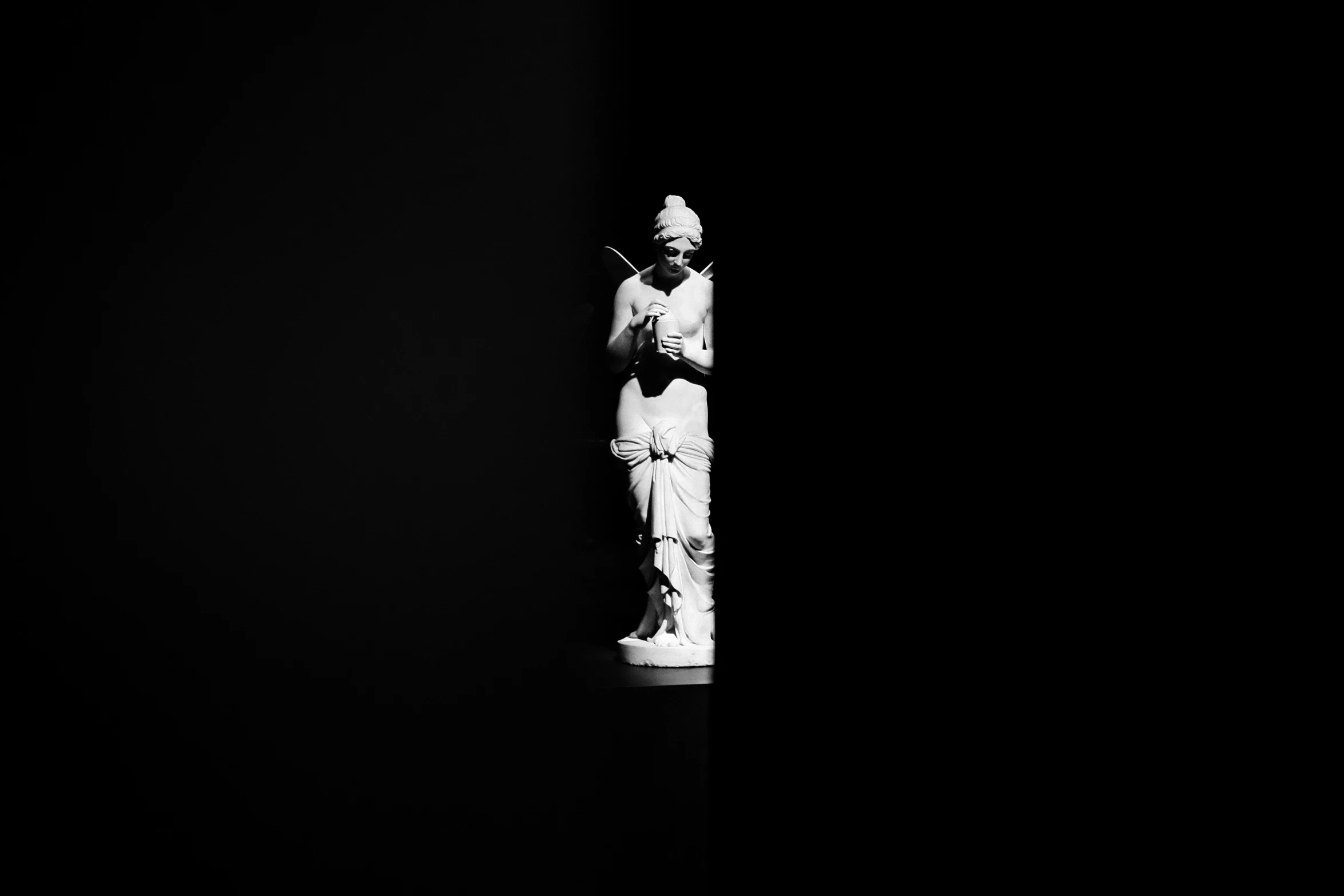 a statue standing next to a black wall