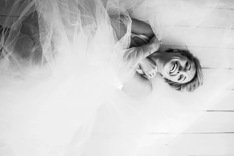 a woman that is wearing a white dress laying down on the floor