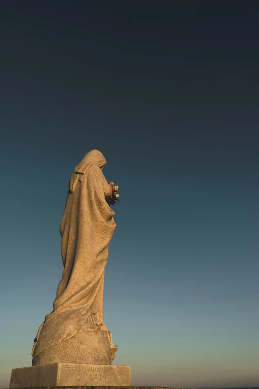 an old statue of a nun sitting in front of water