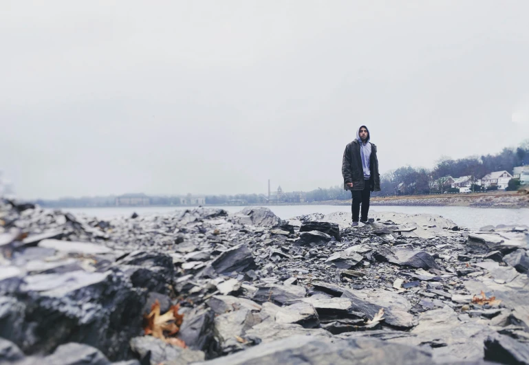 a man standing on some rocks next to the ocean