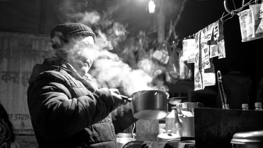 a man standing in a room cooking on top of a pan