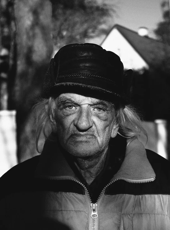 an old man in a jacket and hat standing