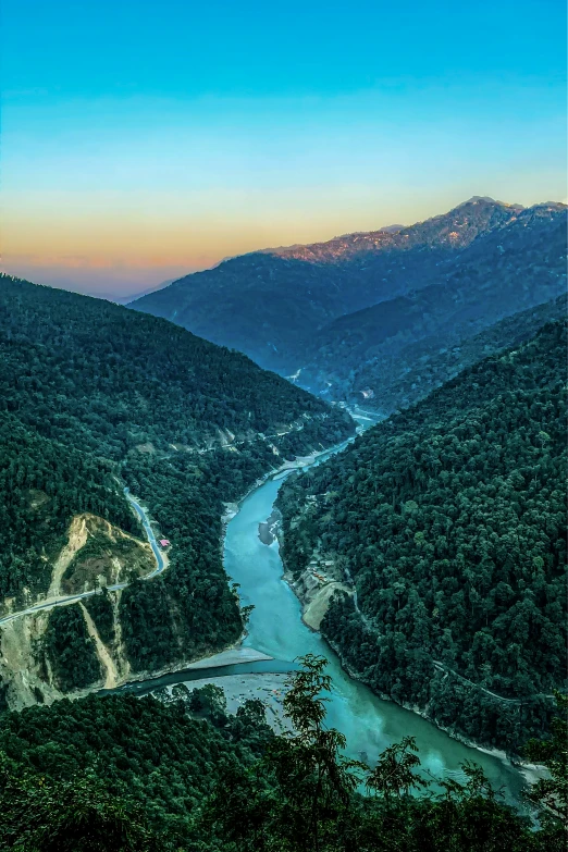 the river is running through a forested mountain valley