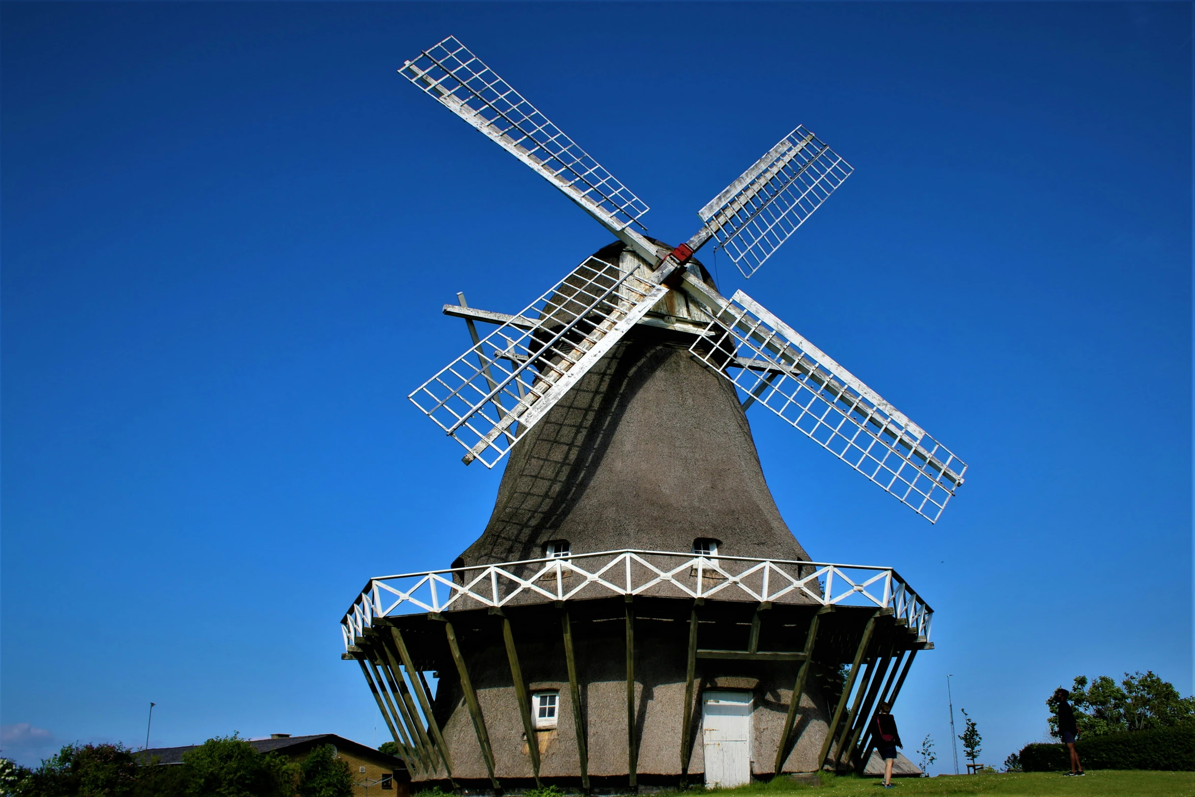 a white windmill on top of a grass covered hill