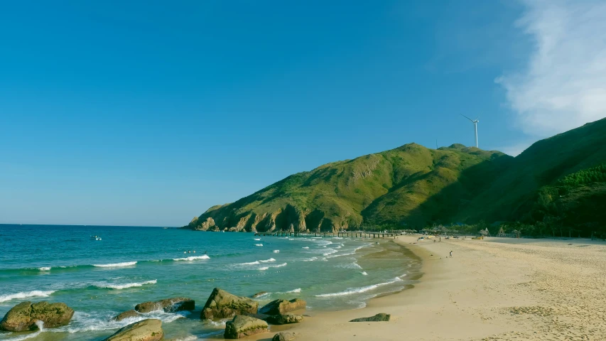 a beach is shown in the foreground and a small mountain rises above the beach