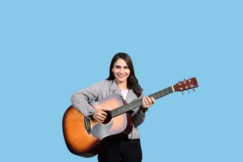 a young woman with an acoustic guitar on a blue background