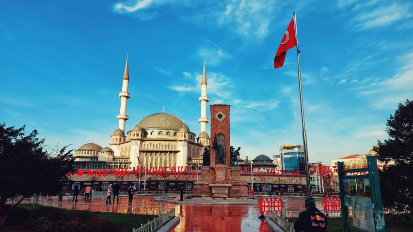 there is a red and white flag on a tower in the middle of an area with people