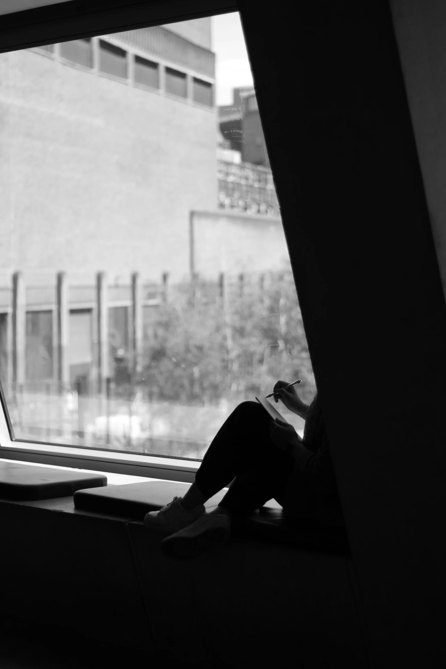 a woman laying on a window ledge while reading a book