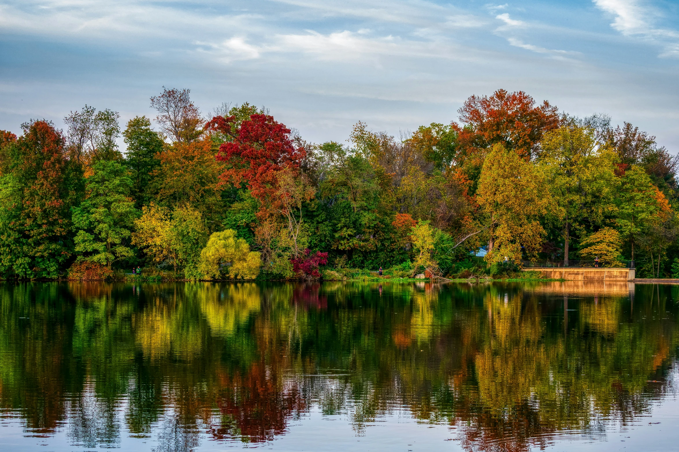 a lake in the middle of fall with red and yellow trees