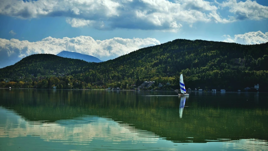 the boat is on the still water near mountains