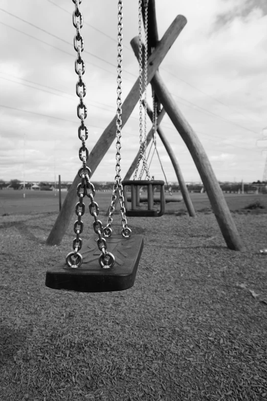 black and white pograph of a swing set in a park