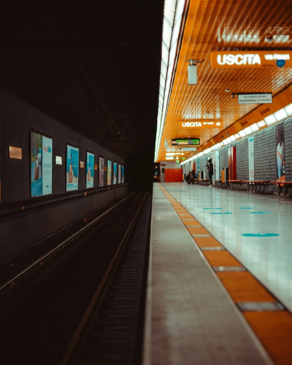 a large empty subway station with posters on it's side