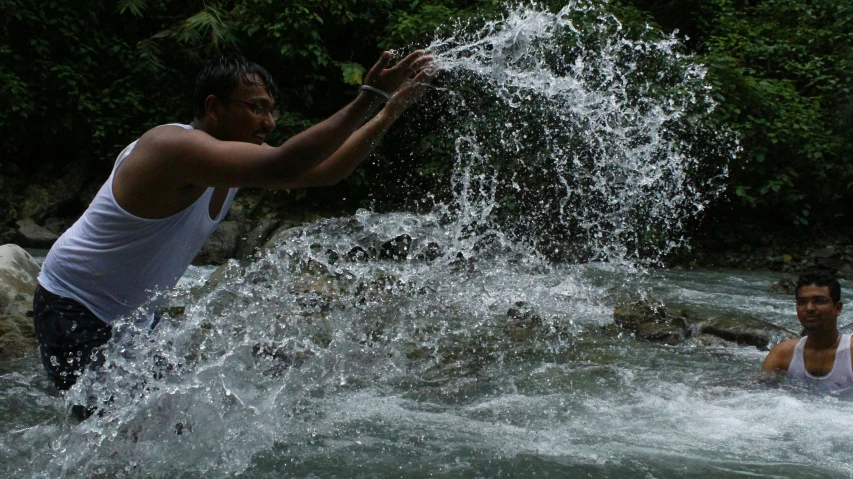 two men playing in water near a group of people