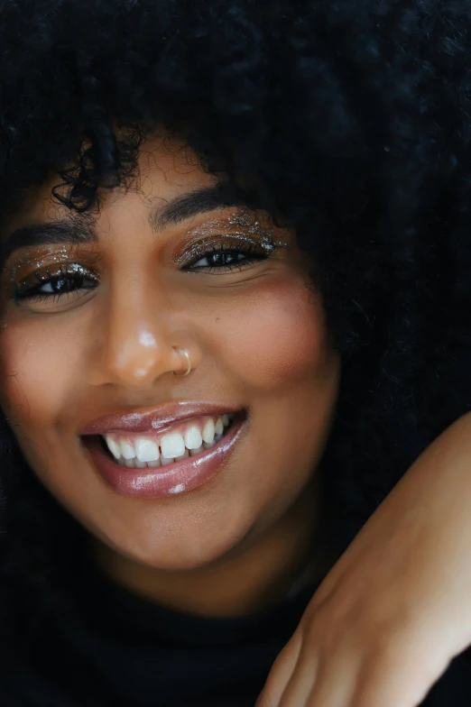 a close - up po of a smiling woman with large, afro hair