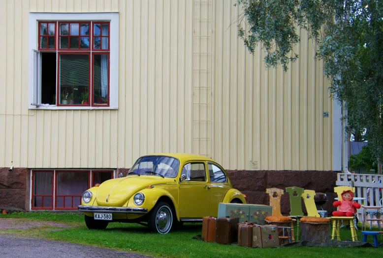 yellow vw bug sitting on top of a grass covered field