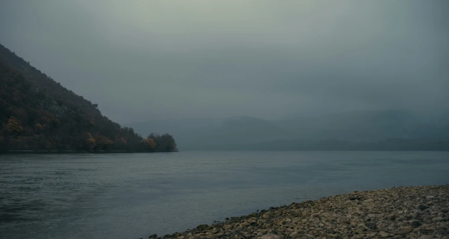 a lake in a foggy area with several hills behind it