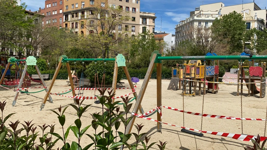 several children's playgrounds and swings in the sand in a city park