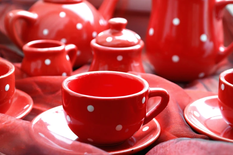 red tea cups and saucers are arranged on plates