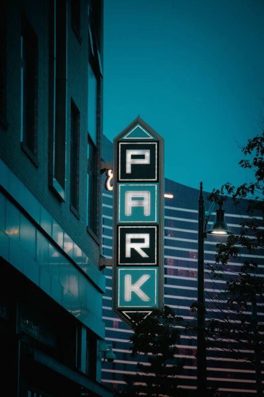 parking sign lit up in the dark with building behind it