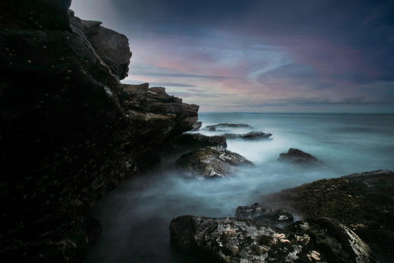 a long exposure picture shows waves coming into rocks