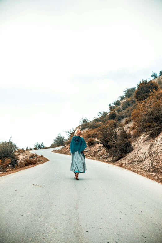 a woman walks on a mountain road talking on her cell phone