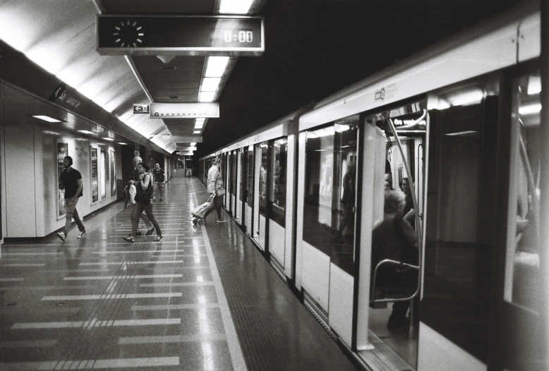 people are walking through a subway station under a light