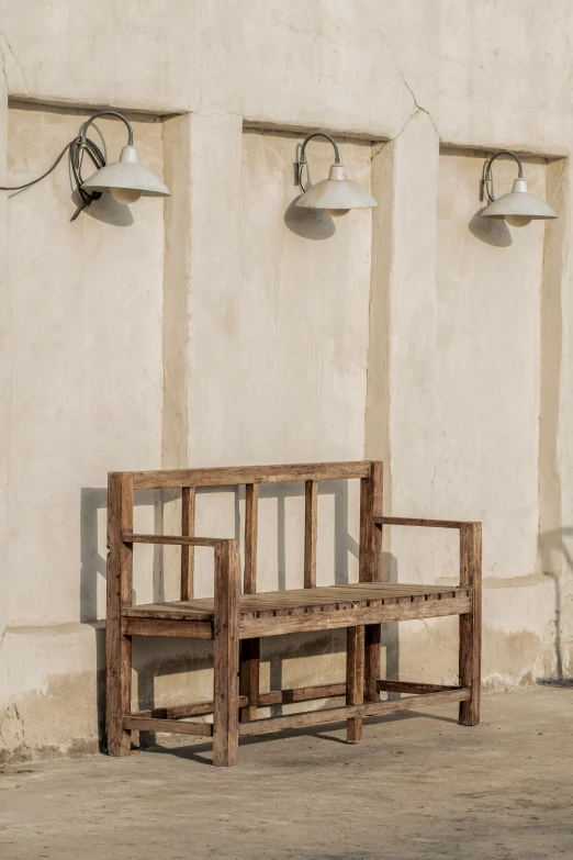 a bench and wall sconces stand against a cement wall