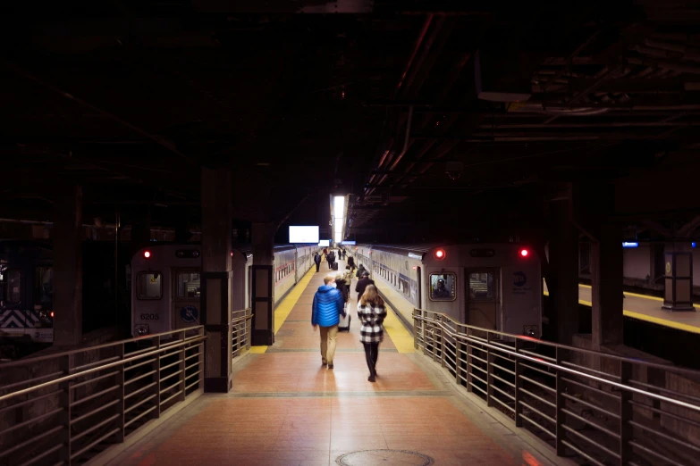 two people walking toward the end of a subway