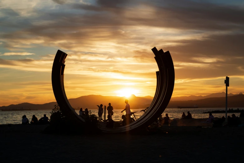 a group of people hanging out at the beach at sunset