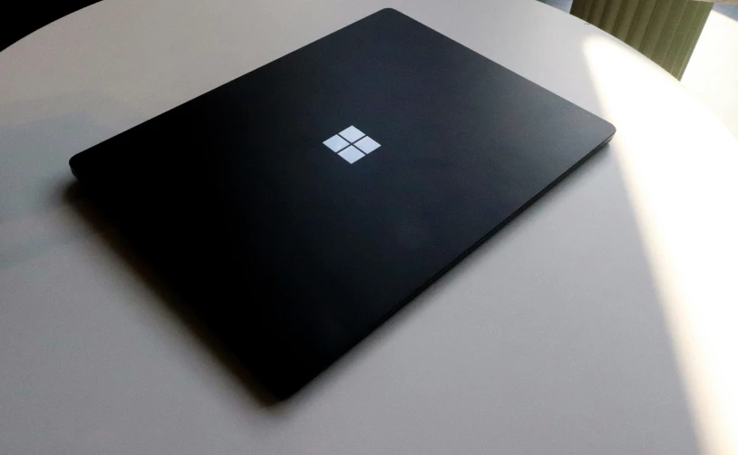 a black surface laptop on top of a white table