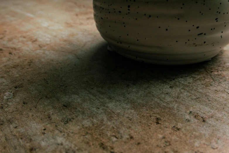 a white ceramic vase with speckled cement