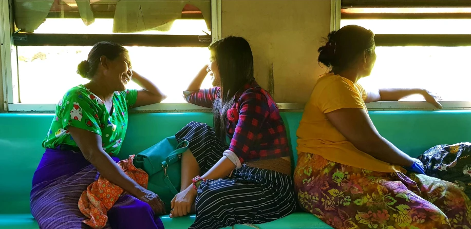 a group of women siting on a green bench