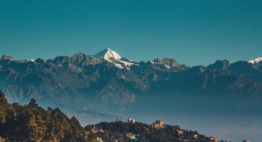 a mountain range covered in snow next to buildings